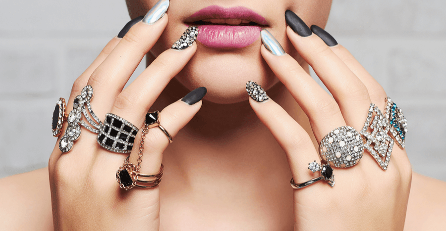 Female's over accessorized hands with rings and nail polish touching her face